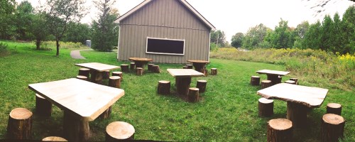 An outdoor blackboard with several wooden tables and seating.