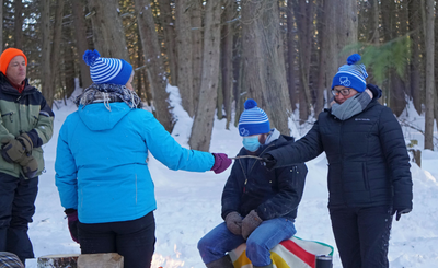 A group of people passing a stick in winter on a trail.