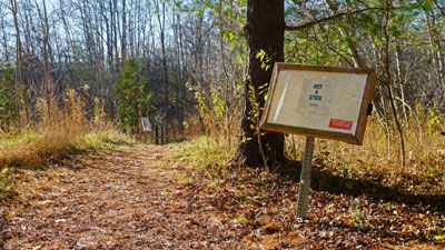 Forested trail with signs holding book pages along the side